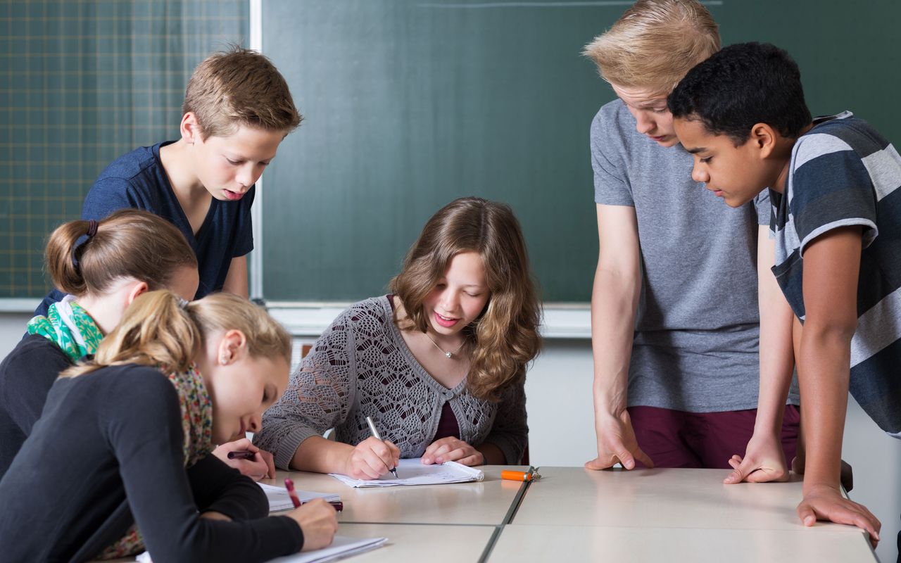 Un enseignant accompagne un petit groupe d’élèves autour d’une table.